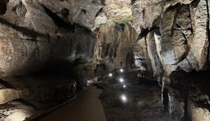 Lit cave path with rock formations.