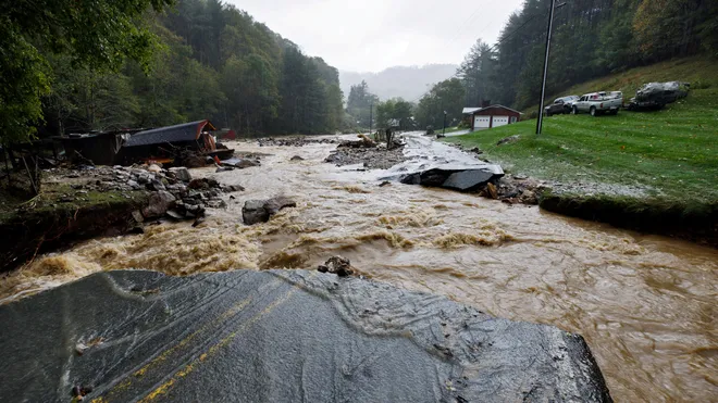 Flooded river with debris and a damaged road.