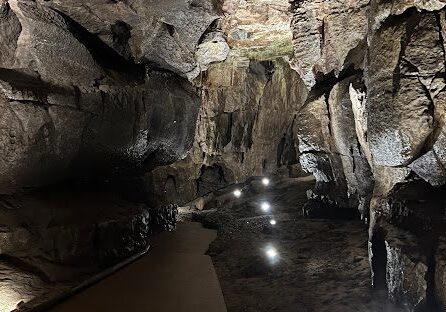 Lit cave path with rock formations.